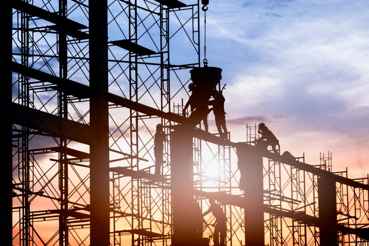 Workers on scaffolding against sunset